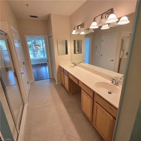 Bathroom featuring a stall shower, double vanity, and light tile patterned floors