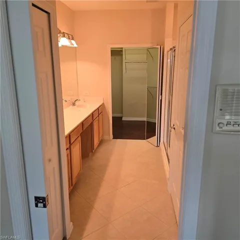 Full bath with vanity, a walk in closet, light tile patterned floors, and a shower stall