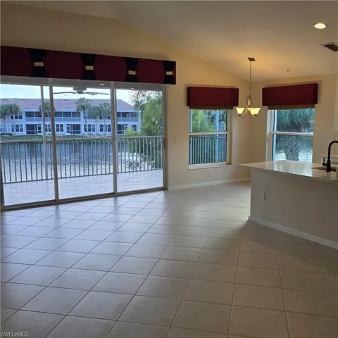 Unfurnished room featuring a water view, lofted ceiling, healthy amount of natural light, and light tile patterned floors