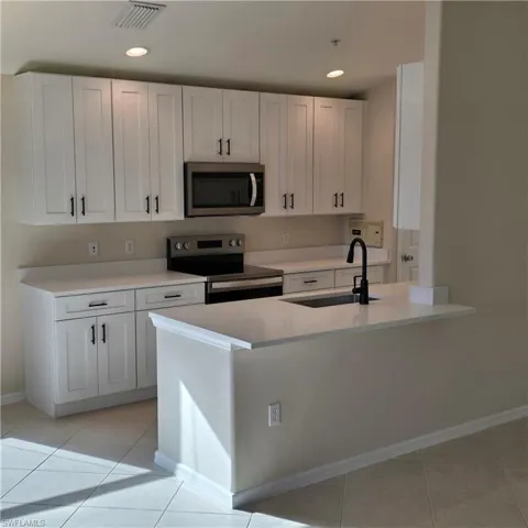 Kitchen featuring white cabinetry, appliances with stainless steel finishes, light tile patterned flooring, and recessed lighting