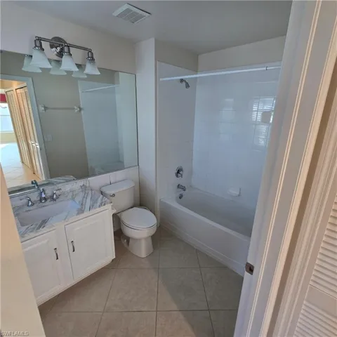 Full bath with vanity, washtub / shower combination, and light tile patterned floors