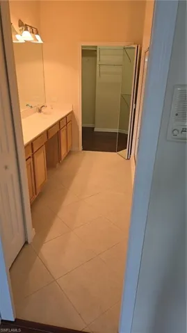 Bathroom with a walk in closet, vanity, and light tile patterned flooring