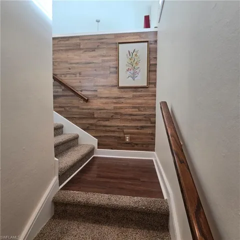 Staircase featuring a textured wall and wood finished floors