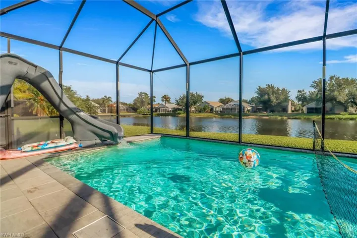Outdoor pool featuring a water view, a water slide, a lanai, and a patio area