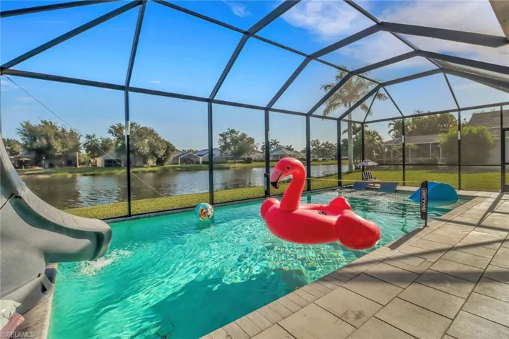 Pool with a lanai, a water view, a patio area, and a water slide