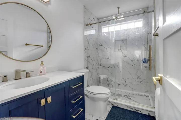 Full bath featuring vanity, a marble finish shower, and toilet