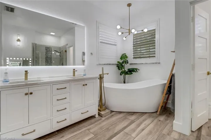 Full bathroom featuring visible vents, a shower stall, a sink, and wood finished floors