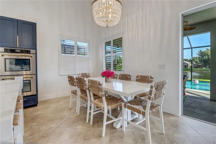 Dining room featuring light tile patterned floors, baseboards, a towering ceiling, and a notable chandelier
