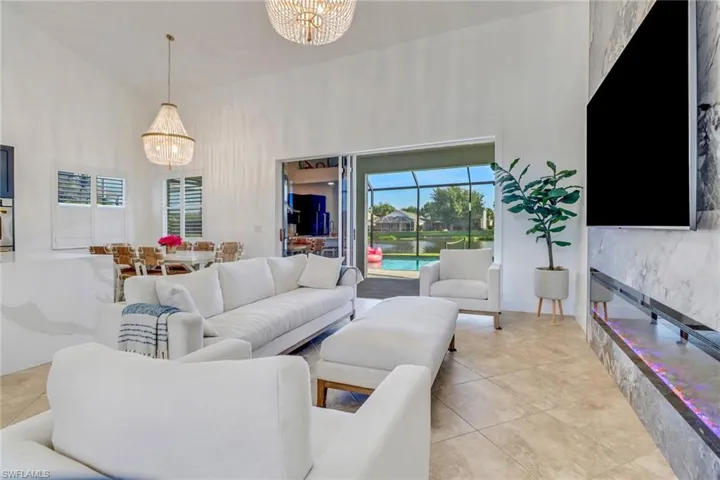 Living area featuring light tile patterned flooring, a notable chandelier, and a towering ceiling
