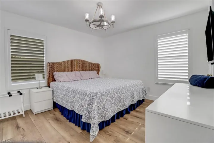 Bedroom featuring baseboards, a notable chandelier, and light wood-type flooring