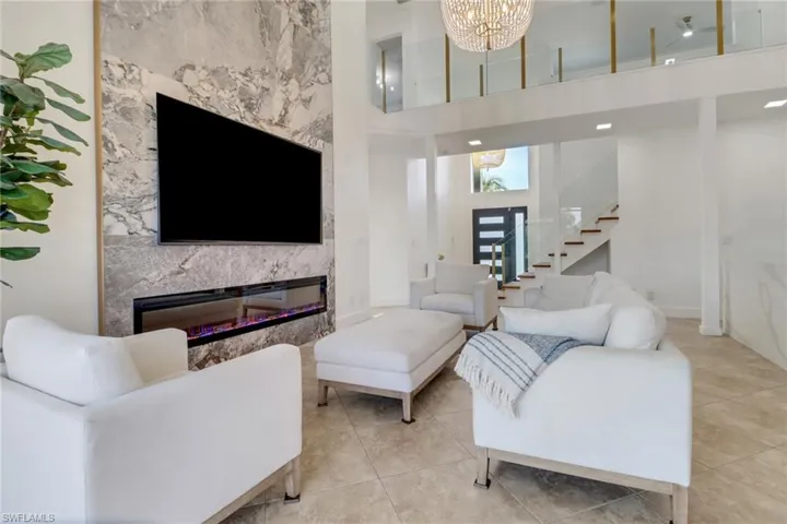 Tiled living area with an inviting chandelier, a towering ceiling, a fireplace, baseboards, and stairway