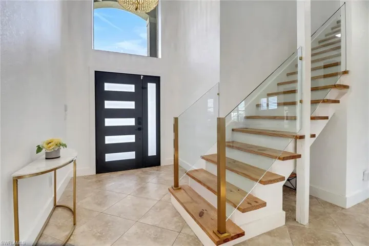 Tiled entryway featuring stairs, a high ceiling, and baseboards