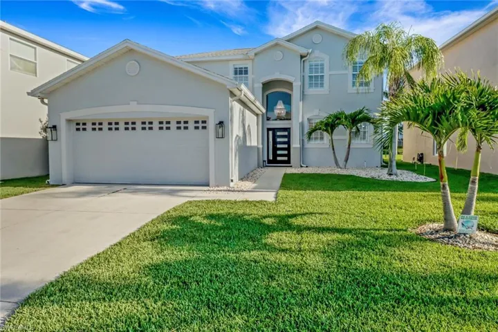 View of front of property with concrete driveway, an attached garage, a front lawn, and stucco siding