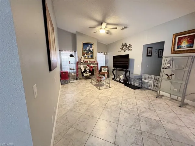 Living area featuring a ceiling fan, vaulted ceiling, and a textured ceiling
