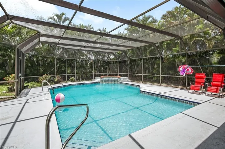 View of swimming pool with glass enclosure, a pool with connected hot tub, and a patio area