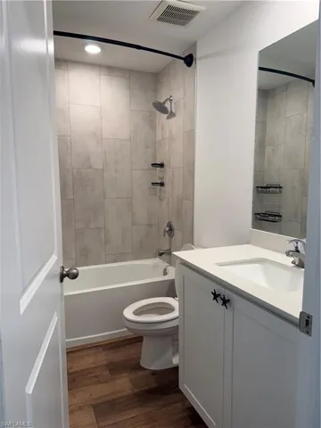 Full bath with vanity, shower / bath combination, and dark wood finished floors