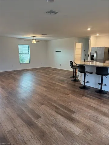View from Dining Room towards unfurnished living room featuring dark wood-style flooring and a sink