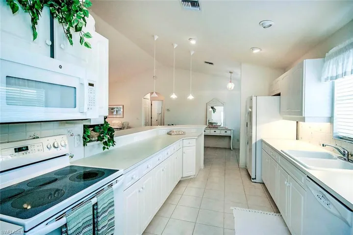 Kitchen featuring white appliances, tasteful backsplash, visible vents, light tile patterned flooring, and a sink