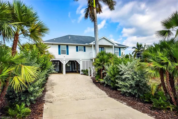 Raised beach house with a carport and driveway