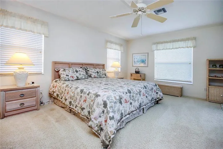 Carpeted bedroom with visible vents, ceiling fan, and radiator