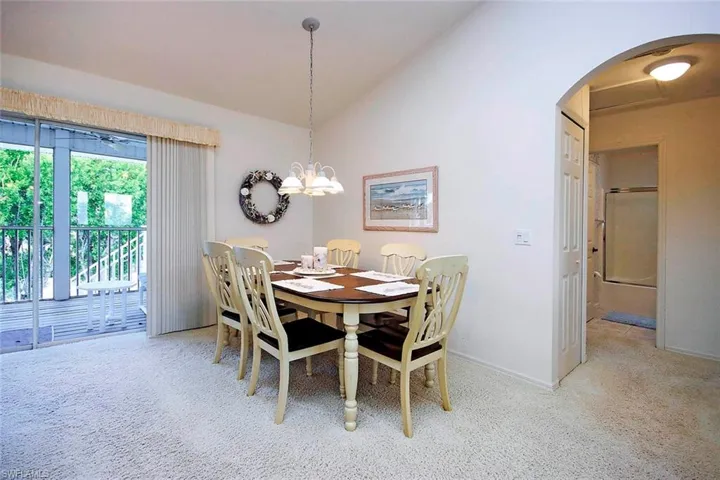Dining space featuring a chandelier, arched walkways, baseboards, and lofted ceiling