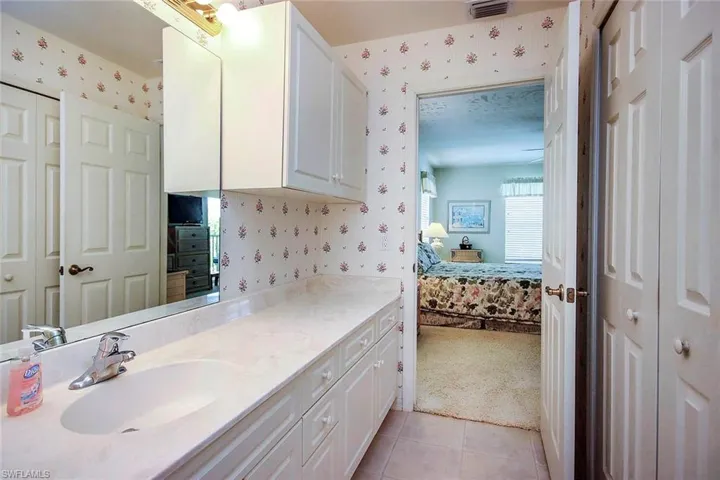 Bathroom with tile patterned floors, vanity, wallpapered walls, and connected bathroom
