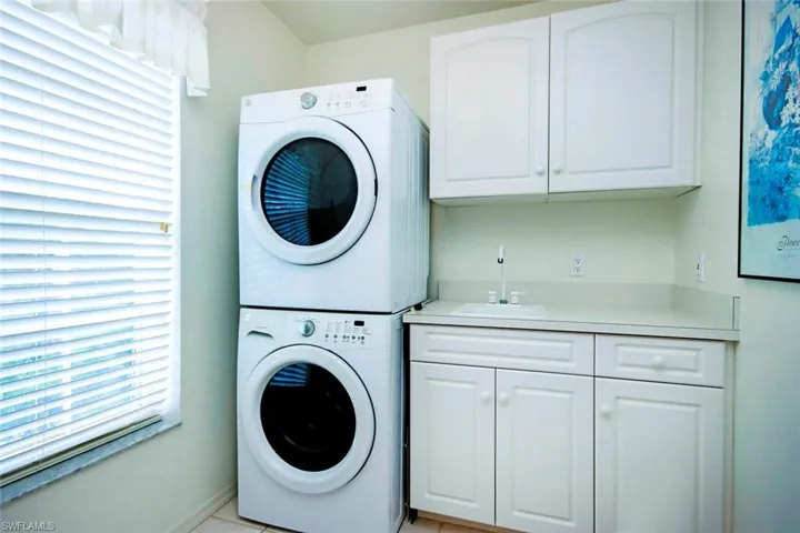 Laundry area with stacked washer / drying machine, a sink, and cabinet space