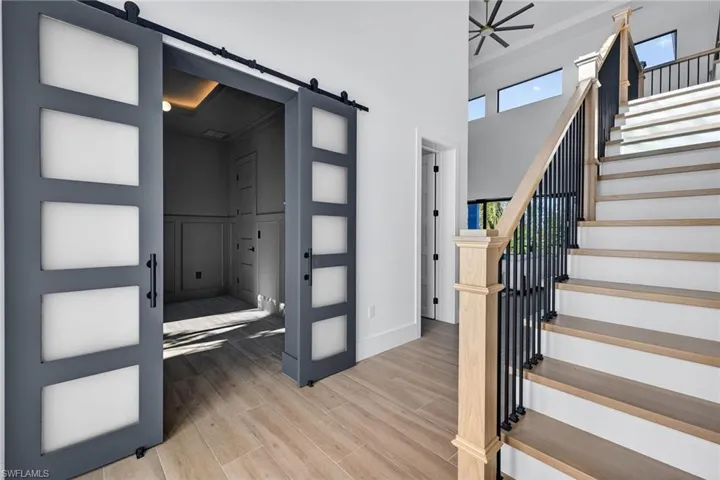 Entrance foyer with a barn door, light wood-type flooring, healthy amount of natural light, a ceiling fan, and a high ceiling