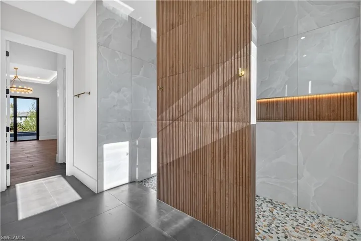 Full bath featuring tile patterned flooring, tile walls, walk in shower, and a chandelier