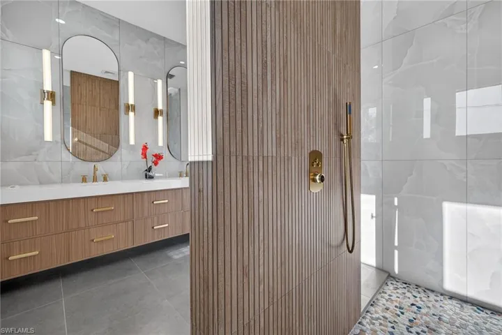 Full bathroom with vanity, walk in shower, dark tile patterned flooring, and tile walls