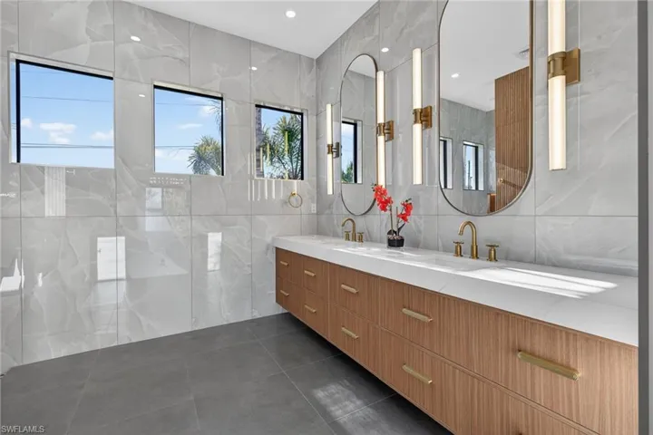 Bathroom with tile walls, double vanity, recessed lighting, and dark tile patterned floors