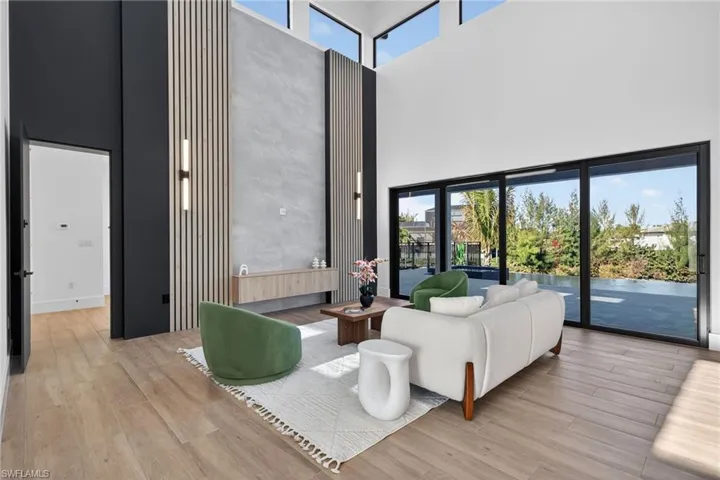 Living area with plenty of natural light, light wood-style floors, and a high ceiling