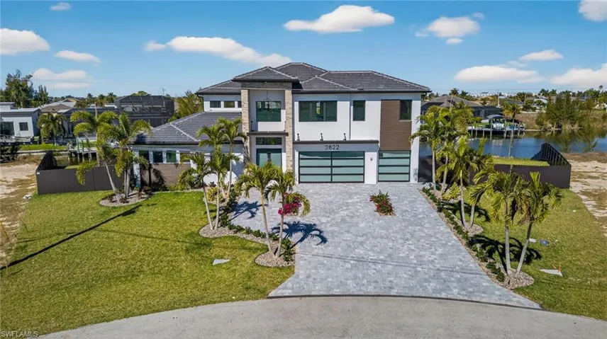 View of front of property with a garage, decorative driveway, stucco siding, a residential view, and a tiled roof