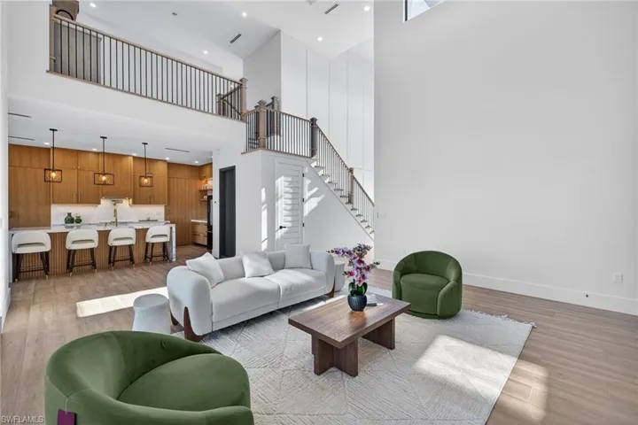 Living room with light wood finished floors, a high ceiling, and recessed lighting