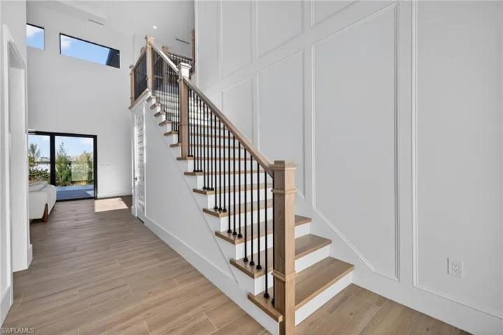 Stairs featuring a decorative wall, wood tiled floors, and a high ceiling
