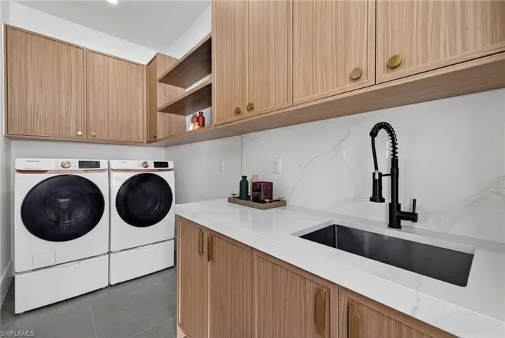 Laundry area featuring cabinet space, separate washer and dryer, and dark tile patterned floors