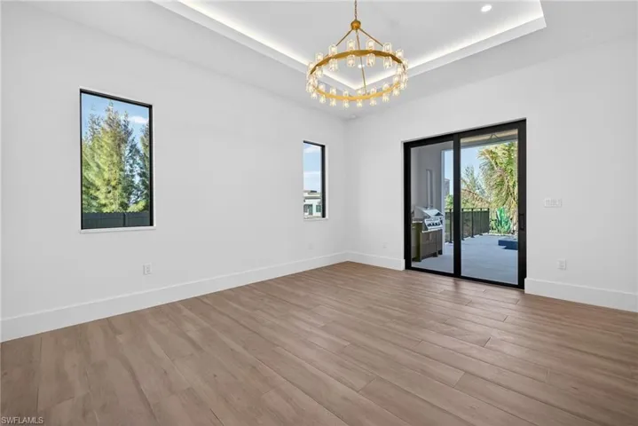 Unfurnished room featuring suspended lighting, a tray ceiling, and light wood finished floors