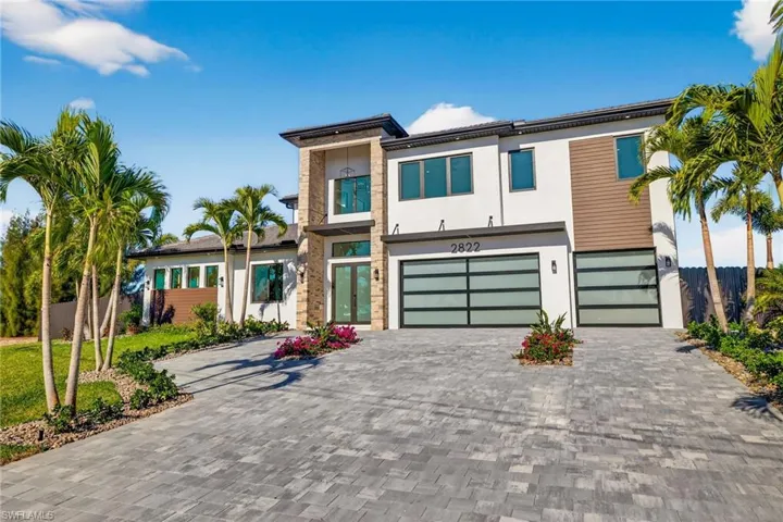 Modern home featuring stucco siding, decorative driveway, and a garage