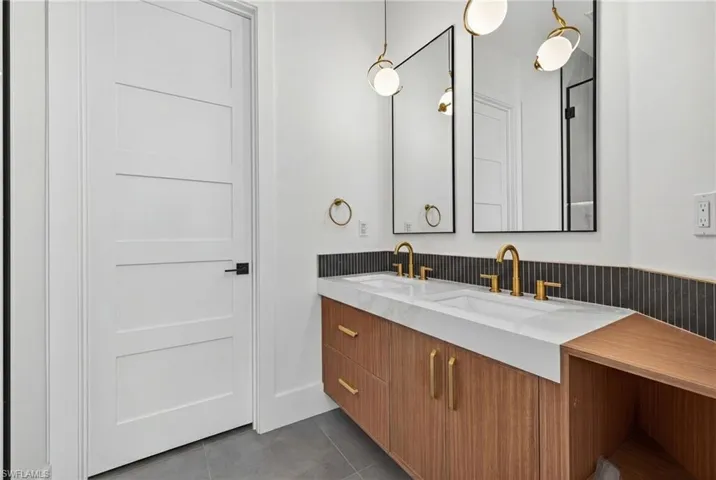Full bath with double vanity and dark tile patterned floors