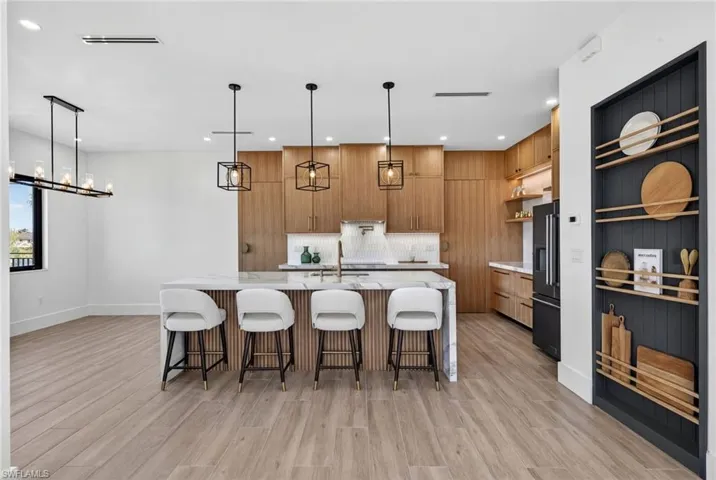 Kitchen with light stone counters, a kitchen breakfast bar, light wood-type flooring, a large island, and modern cabinets