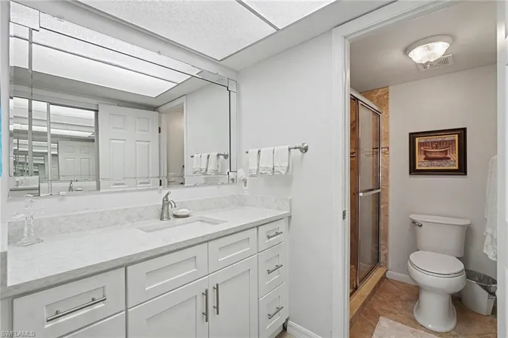Full bath with a stall shower, vanity, and light tile patterned floors