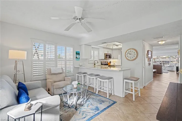 Living area with ceiling fan, a textured ceiling, healthy amount of natural light, and light tile patterned floors