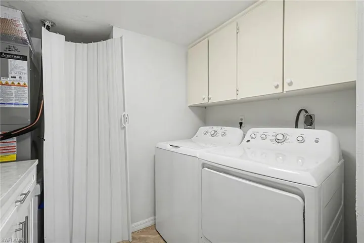 Laundry room featuring cabinet space, washing machine and clothes dryer, and heating unit