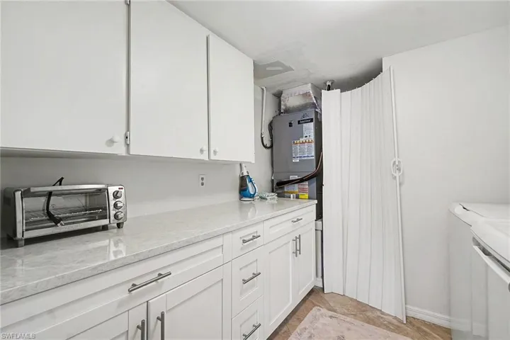 Washroom featuring cabinet space, heating unit, and washing machine and clothes dryer
