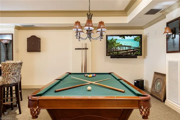 Recreation room featuring pool table, crown molding, a chandelier, carpet flooring, and a tray ceiling