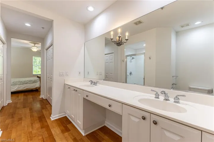 Full bath featuring double vanity, a shower stall, wood finished floors, a chandelier, and ensuite bathroom