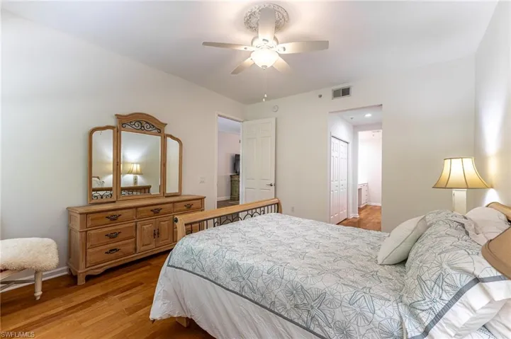 Bedroom with light wood-style flooring, a closet, a ceiling fan, and ensuite bath