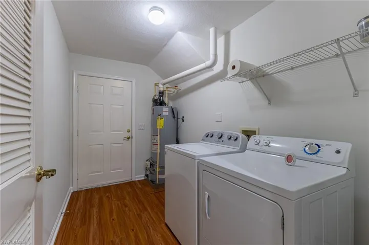 Laundry room with separate washer and dryer, dark wood-type flooring, a textured ceiling, and water heater