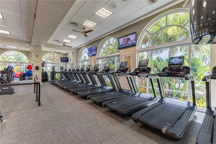 Exercise room with carpet, a ceiling fan, and a drop ceiling