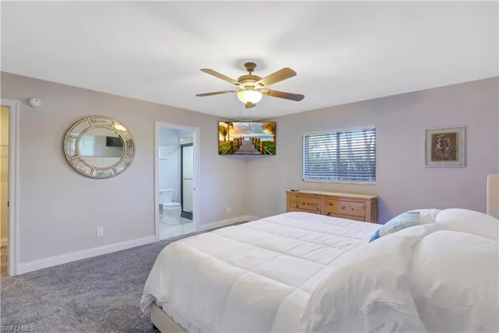 Carpeted bedroom with a ceiling fan and ensuite bathroom